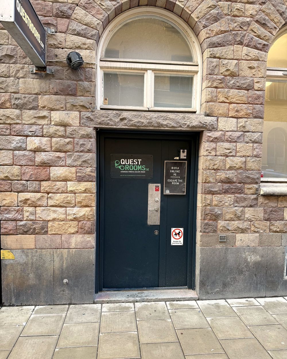 The entrance at Kocksgatan 21A: a black door with the Questrooms sign and the doorbell